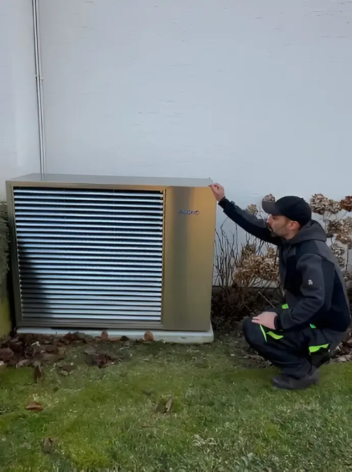 Vérification professionnelle de pompe à chaleur pour un fonctionnement optimal Technicien inspectant une pompe à chaleur installée dans un jardin résidentiel