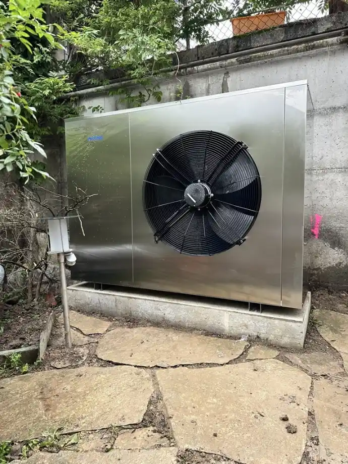 Pompe à chaleur puissante pour usage résidentiel ou commercial en Suisse romande Pompe à chaleur extérieure de grande capacité installée contre un mur en béton en Suisse romande
