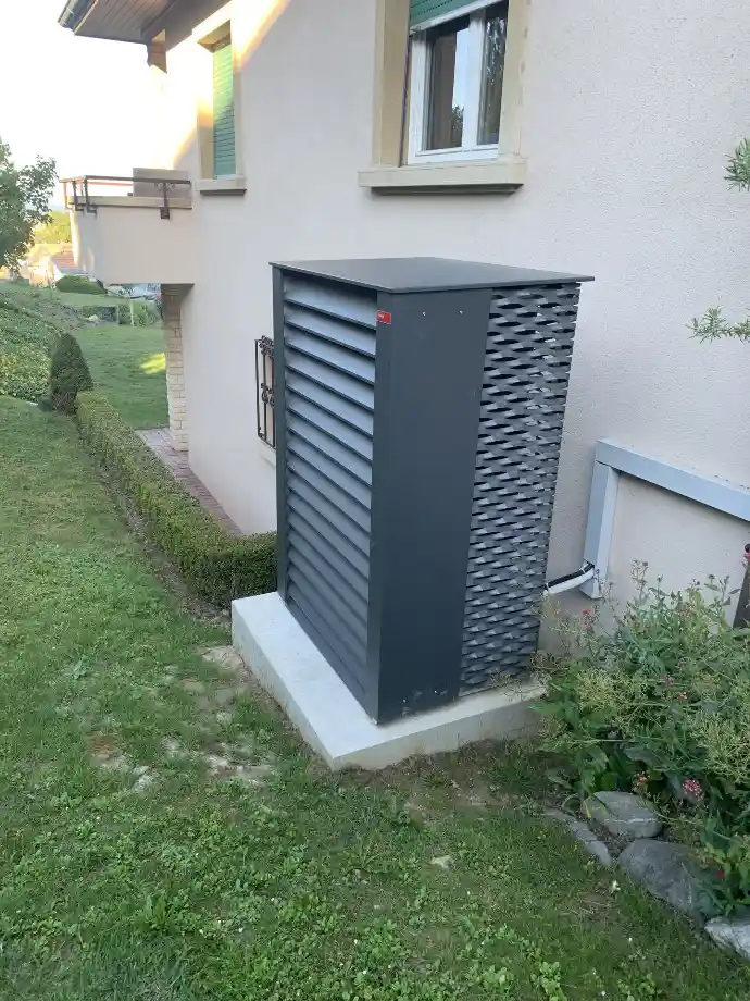 Installation d’une pompe à chaleur pour maison individuelle en Suisse romande Pompe à chaleur compacte et moderne installée à l’arrière d’une maison individuelle en Suisse romande