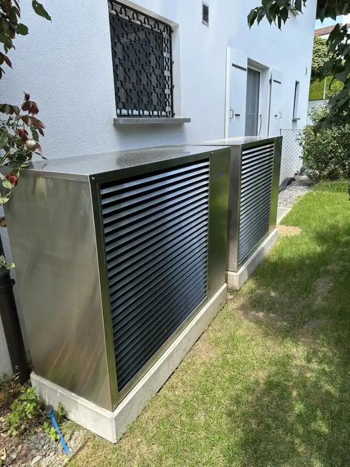 Installation double de pompes à chaleur résidentielles en Suisse romande Deux pompes à chaleur résidentielles installées côte à côte sur un mur extérieur en Suisse romande